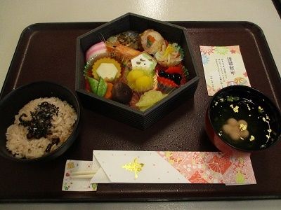 海老や栗きんとんや黒豆の入ったおせち料理と赤飯と吸い物のセット
