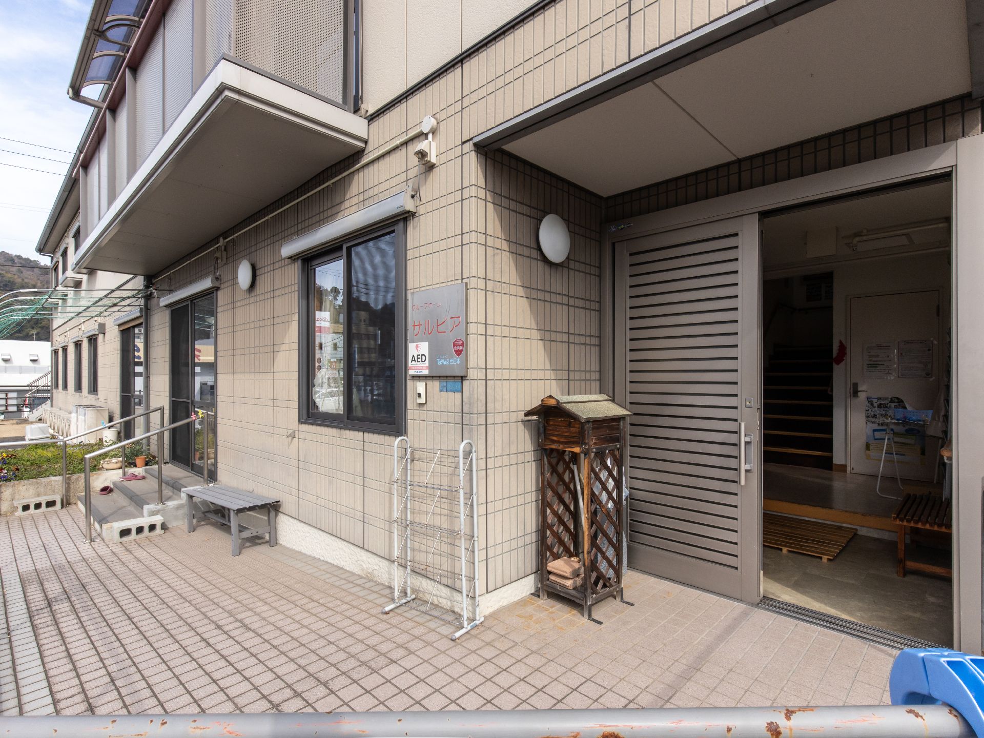 落ち着いた色合いの外装で、２階建ての集合住宅のような外観。エントランスのドアは引き戸なので簡単に開閉することができる。