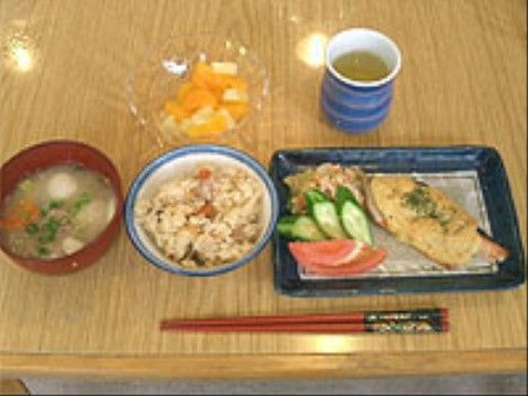 魚のマヨネーズ焼きにトマトやキュウリが添えられた一皿のある食事