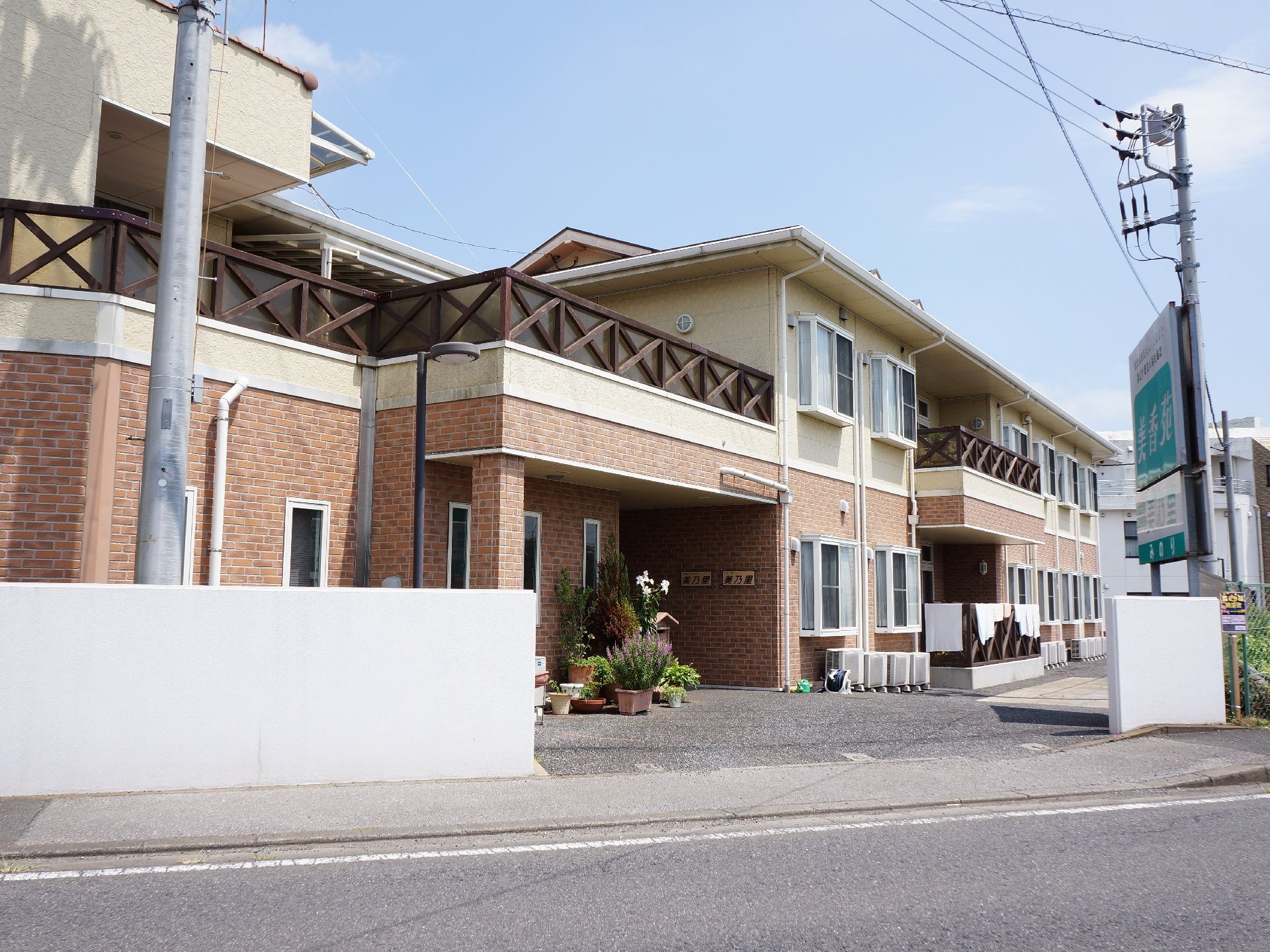 ツートンカラーで2階建ての建物である。道路に面している。障害物がないので日当たりが良い。2階には、テラスがある。