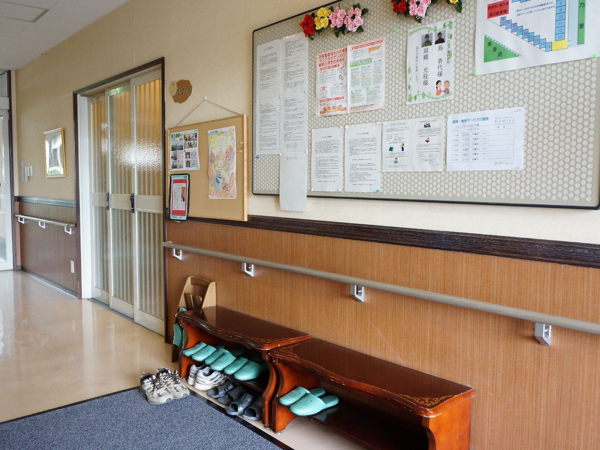 エントランスには、安全を保つために手すりが付いている。掲示物が貼ってある掲示板もある。来客用のスリッパ置き場がある。