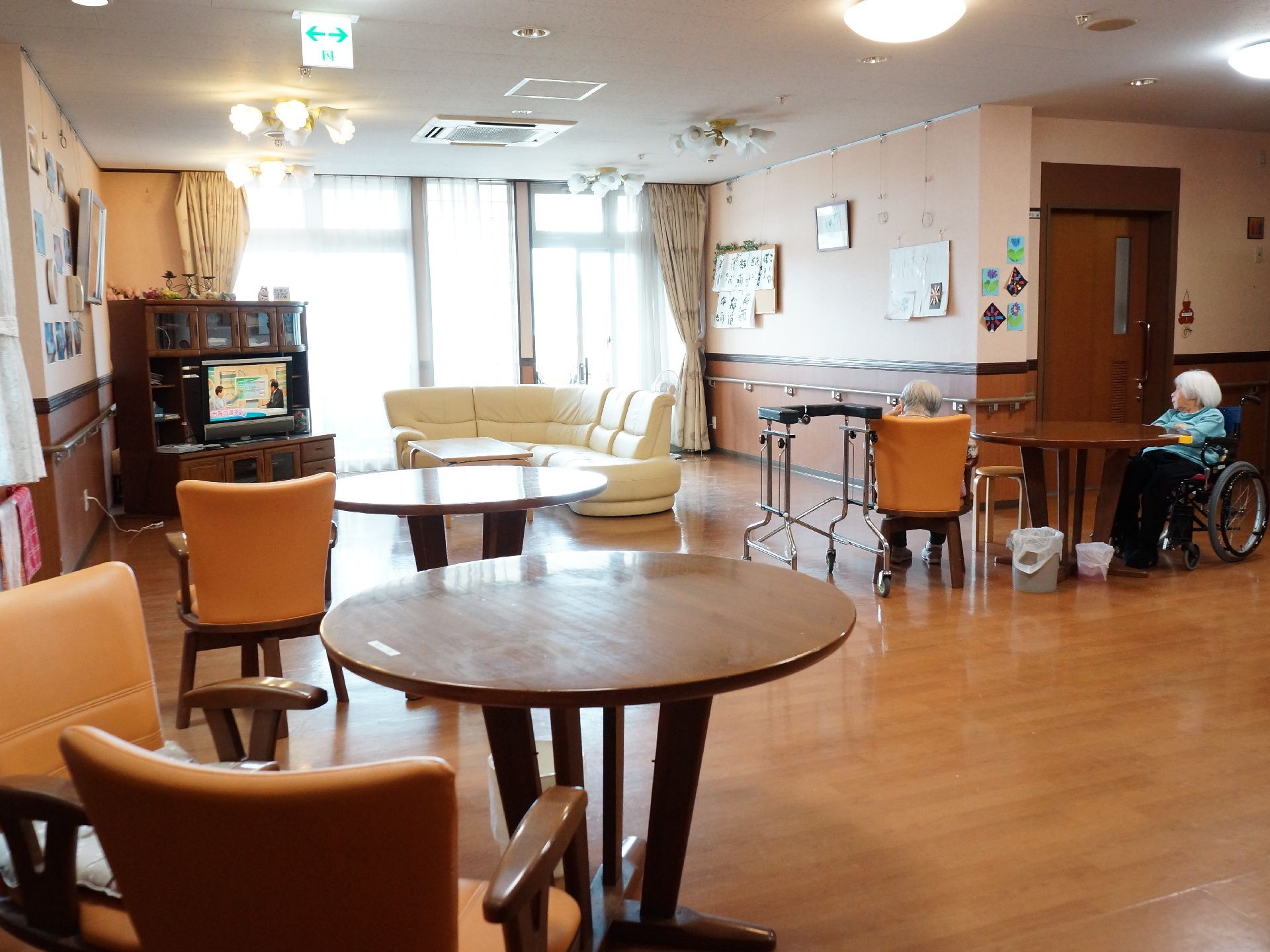 丸テーブルが設置されているリビングで、テレビ鑑賞をする二名の入居者