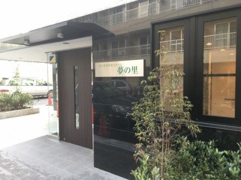 建物前に植物が植えられ、外壁が黒色で光っている施設外観
