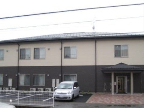 建物の右手に玄関がある、二階建てのシックな色合いをした施設外観