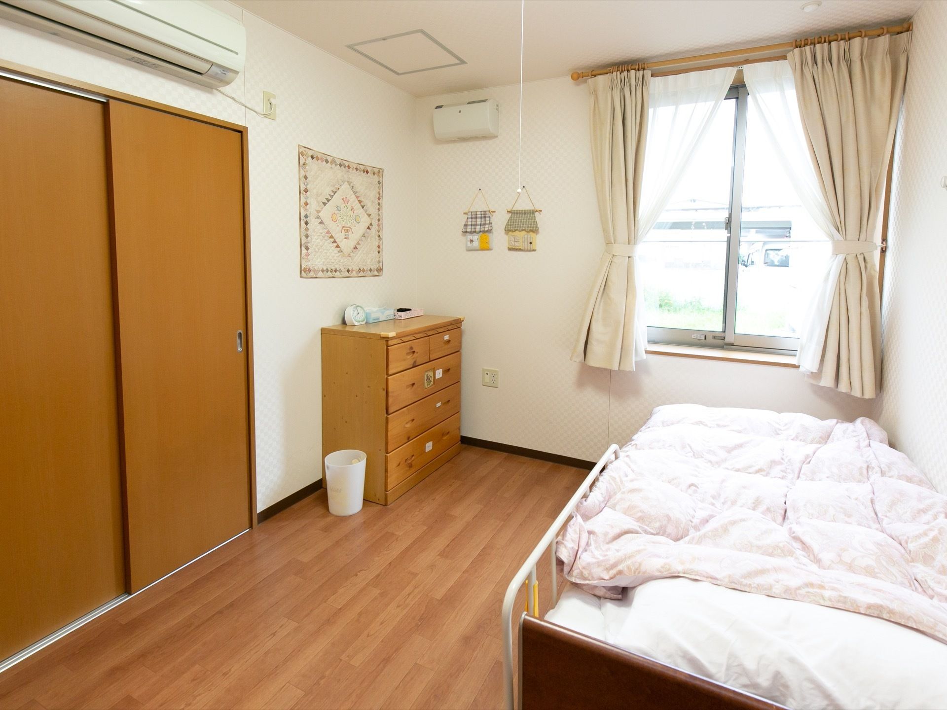 居室の入り口側から内部を見た図である。左手には大きな収納とチェストが並んでいる。右手にベッドがある。