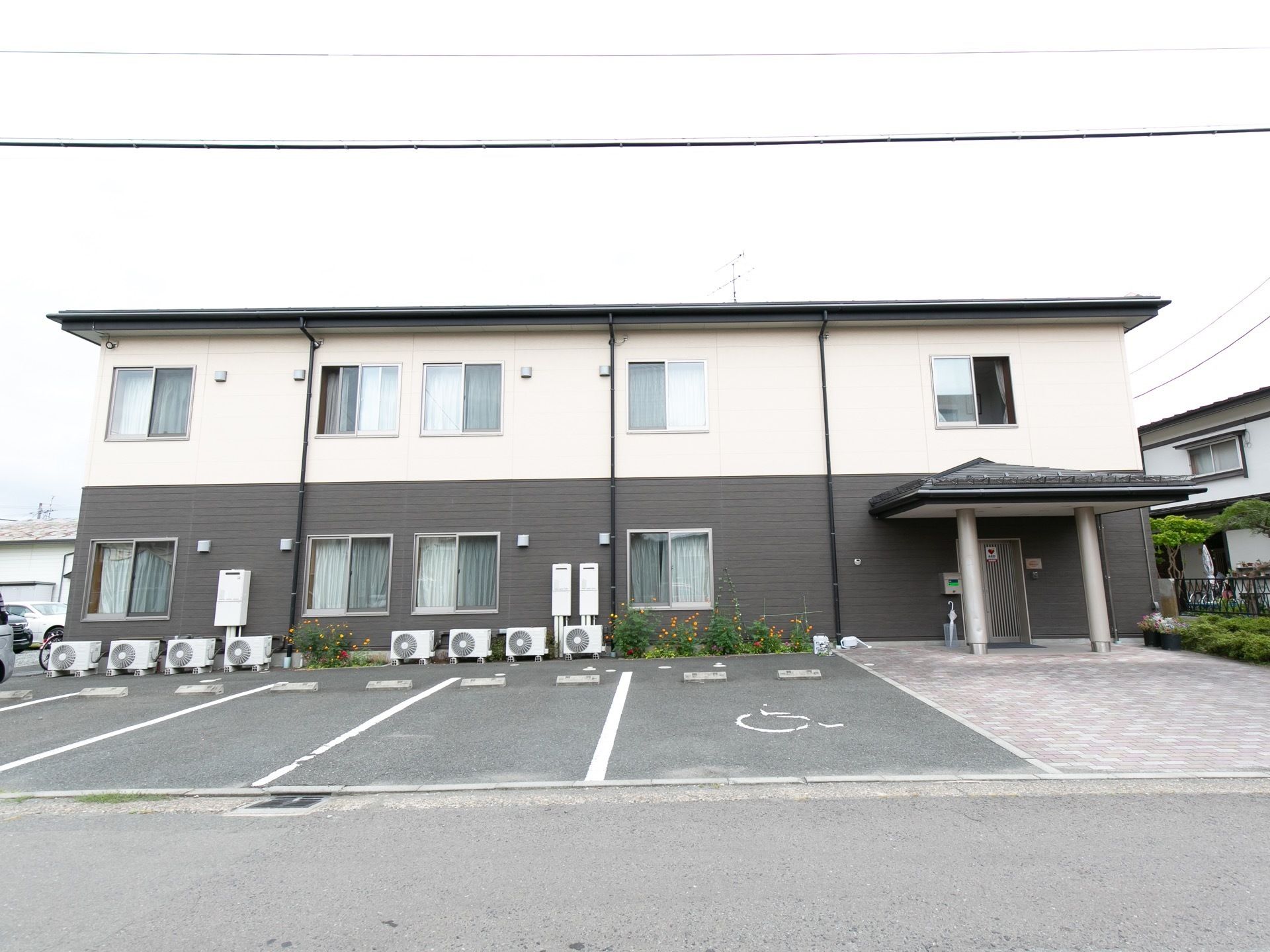 ２階建ての建物で、１階部分が黒、２階部分が白に塗り分けられている。施設の前は駐車スペースが並んでいる。