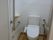 便器の両側に手すりが設置されたトイレである。白く清潔感があり、壁には緊急時呼び出しボタンが備わっている。