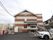 施設は２階建てで、三角形の屋根がのっている。屋根の下に丸型の窓が開いている。施設前は駐車スペースが広がっている。