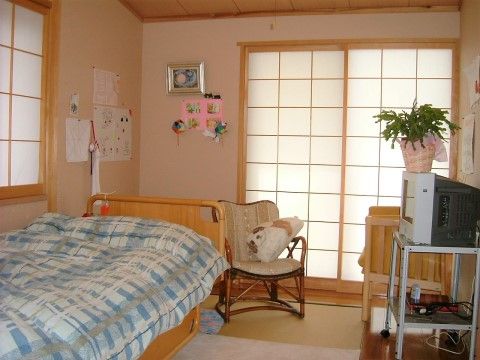 居室にはベッド、テレビ、１人掛け用の椅子が２脚置かれている。壁は絵や飾り物が貼ってあり自分流の居室となっている。