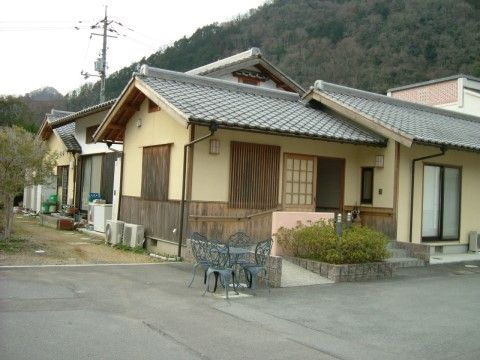 近くに山が見えるのどかな雰囲気の場所に１階建て民家風の建物が並んでいる。玄関先には天気のいい日に談笑ができるガーデンセットが置かれている。