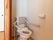 居室にがあるトイレで、上部には収納棚が設置されている。入口は木製の引き戸で仕切られている。