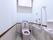 洋式トイレがある。壁に手すりがついている。緊急用ブザーが壁についていて、紐が長く設定してあるので、座ったままでも使える。