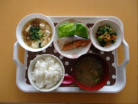 トレイにのせられたご飯、汁物、メインの魚料理、小鉢２品の食事。食べやすく、バランスのとれた食事である。