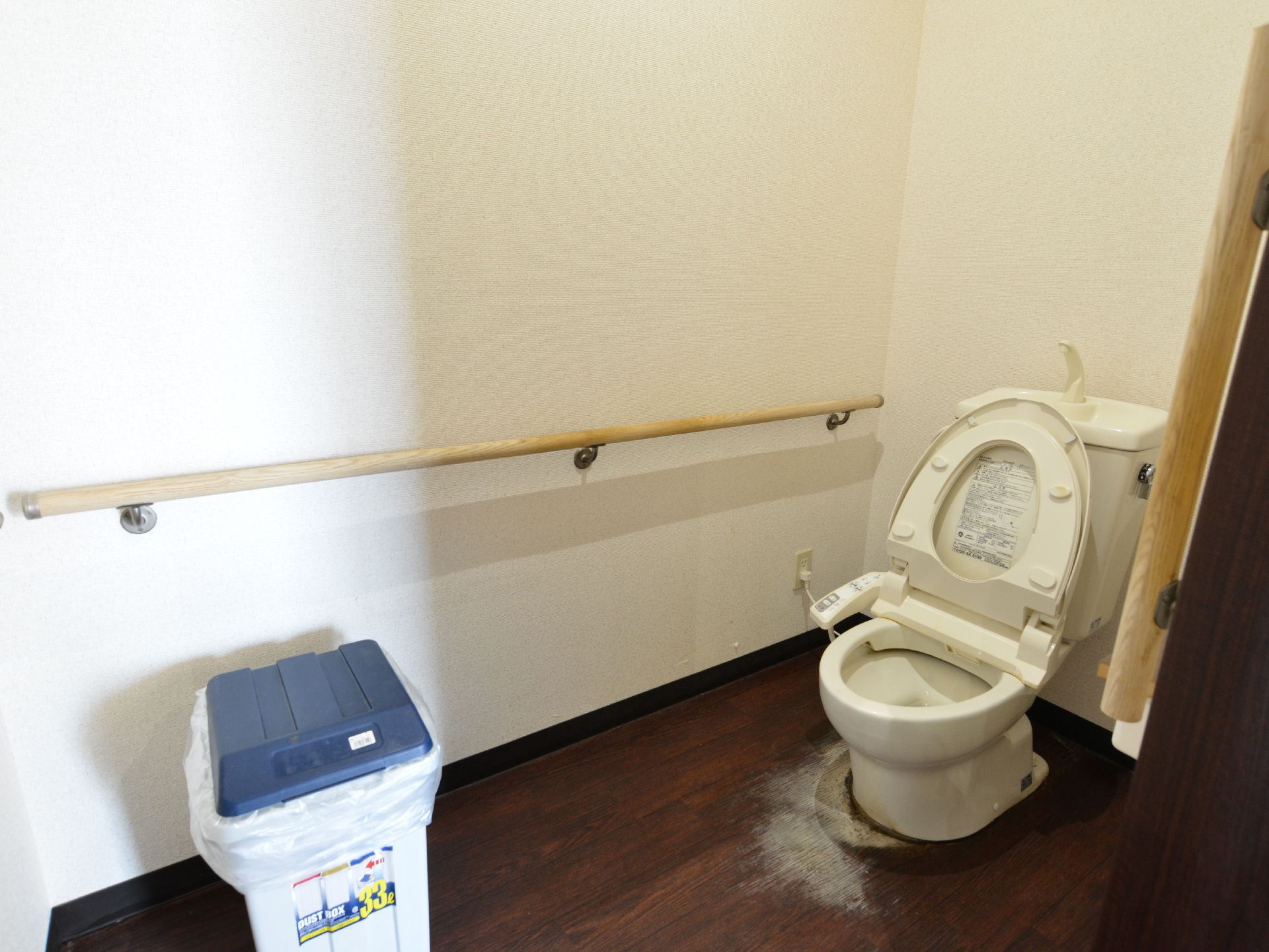 車いすの方がご利用できるよう、トイレは広い空間となっている。壁には手すりが取り付けられ、ゴミ箱も置かれている。