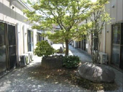 施設の建物の間に設置されている、岩が置かれ植物が植えられているスペース