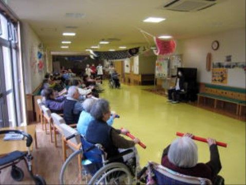 広い部屋の片側に並び、目の前のスタッフを真似て体操をする大勢の入居者