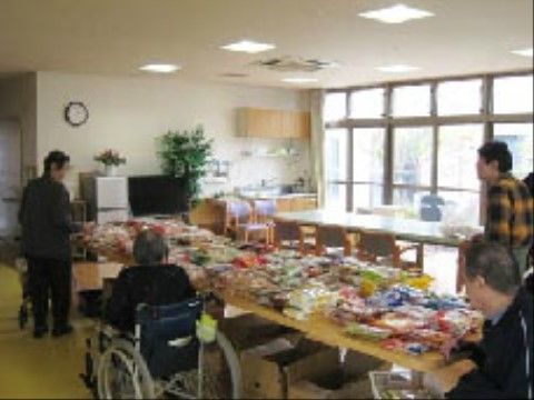 テーブルの上に並べられている品々を見て回っている車椅子の入居者