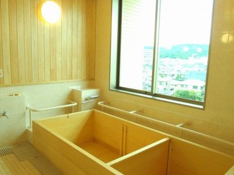 窓の大きな浴室は木製の浴槽にあわせて壁の一部分が木調になっている。浴槽に隣接した２面の壁には手すりが設けられている。