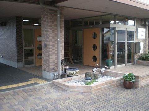 玄関の前に二羽のツルのオブジェが設置されているスペースのある建物