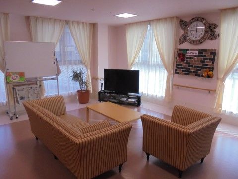 ホワイトボードや新聞、テレビなどが用意されている。壁には大きな時計があり、時間が分かりやすい。手すりも設置されている。