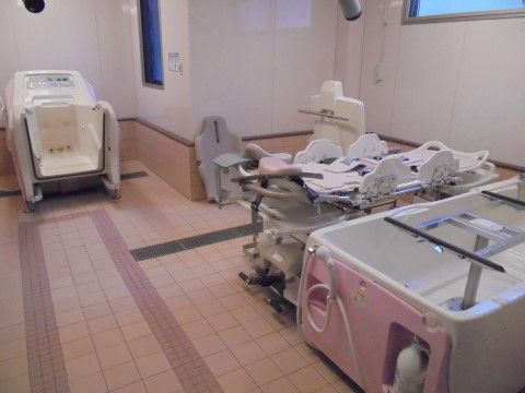 床はピンクのタイルになっており、介護浴槽が設置されている。浴槽の外側にはシャワーが付いている。壁には縦長の窓と、横長の窓がある。