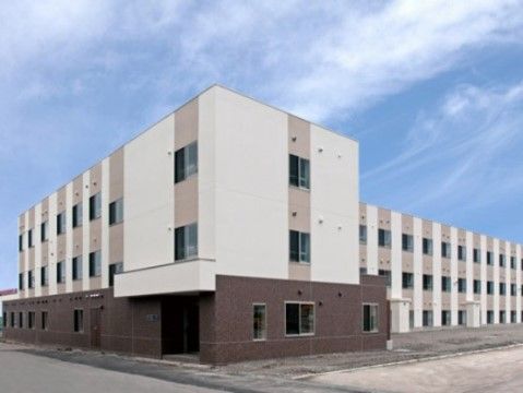 青空の下に映えている、上部が白色で下部がこげ茶色をした施設外観