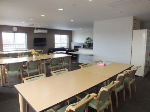 大型テレビが取り付けられたリビング。テーブルとテーブルの間には、車椅子での移動も楽にできるスペースがある。