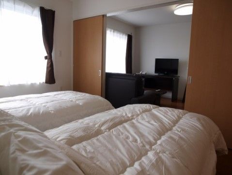 居室にある寝室には、シンプルなベッドが２つ並んでいる。リビングからの扉は引き戸になっており、段差もないため移動が楽にできる。