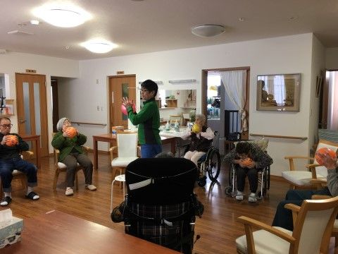 色とりどりのボールを手に持って、スタッフと一緒に体操をする入居者たち