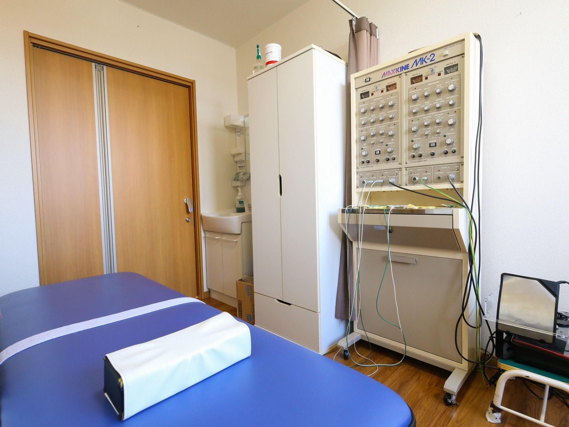 電流を用いた理学療法の機器を備えた部屋がある。ビニールシートのベッドと枕が置かれている。洗面所も用意されている。