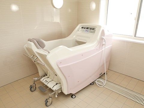 部屋の角に、大きな入浴機器が設置されている窓がある浴室