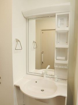居室に設置されている白い洗面化粧台である。身だしなみを整える際に必要なものは、すっきりと収納できるようになっている。
