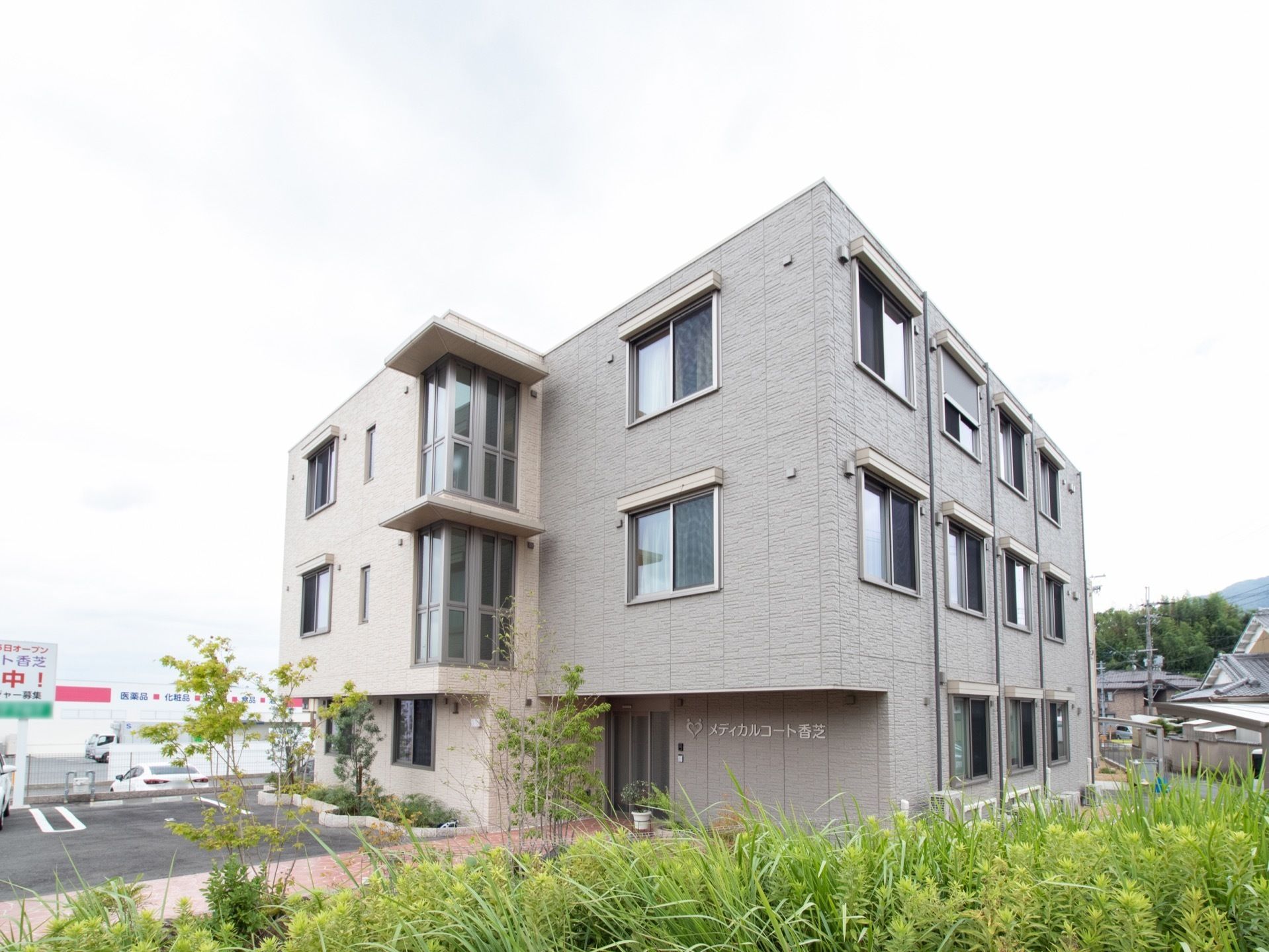 建物はベージュとグレー2色の外壁で、鉄骨造りの3階建てである。1階の軒下の壁に施設の名称が表示されている