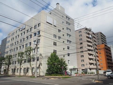 道路向こうから見る、白い外壁をした大きな施設外観の遠景