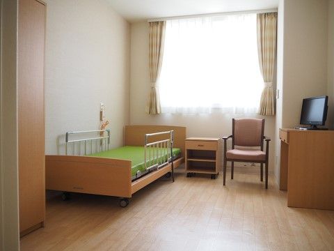 広々とした室内には介護用ベッド、テーブルとテレビが並べられている。その奥に設置されている窓から、明るい光が室内に差し込んでいる。