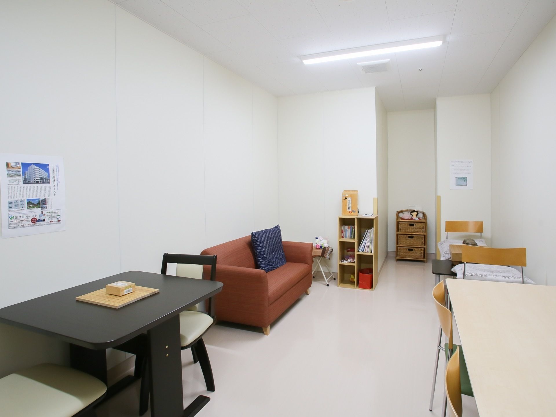 室内に、テーブルや椅子、ソファが置かれている。本や雑誌の入った小さな本棚や、折りたたみ式の将棋盤などもある。