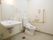 広い個室に、洋式トイレと洗面台がある。便器の横には跳ね上げ式の手すりが備わっている。壁にナースコールが設置されている。