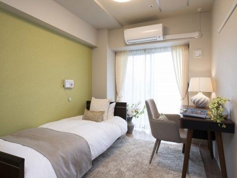 壁が緑色で床にカーペットが敷かれている、ナチュラルな雰囲気の居室
