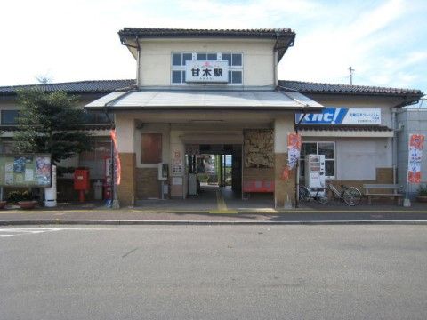最寄の駅。白を基調とした落ち着いた雰囲気の駅舎には、入口に自動販売機やポスト、ロータリーやバス停もある。