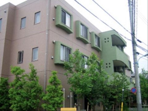 周囲に高い木が植えられている、凹凸のある三階建ての施設外観