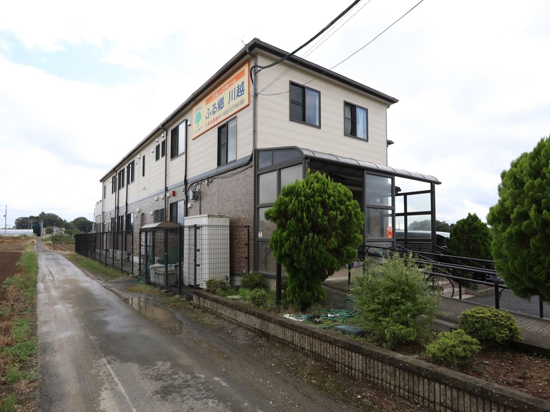 施設は２階建ての建物になっており、２階の壁には施設名が書かれた大きな看板が取り付けられている。側には花壇があり、木などが植えられている。