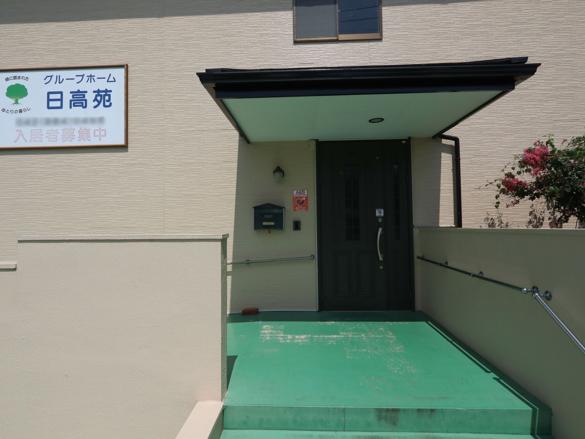 入口は雨除け用の屋根があり、施設名が書かれた看板を備えている。壁に手すりを設置し、安全に移動することができる。