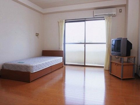 左側にベッドが設置され、反対側にテレビが置かれている居室