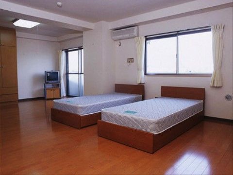 夫婦専用の居室である。広々とした空間には、ベッドが２台、洋服ダンス、エアコン、テレビが備わっている。