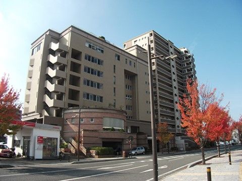 広い道路に面した大きなグループホームである。落ち着いた色合いの建物で、サイドには非常階段が設置されている。