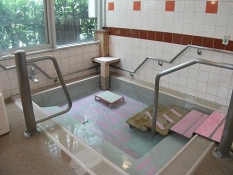 窓から豊かな自然を眺めることができる浴室。浴槽まわりの壁や階段の両サイドには、手すりが設置されている。