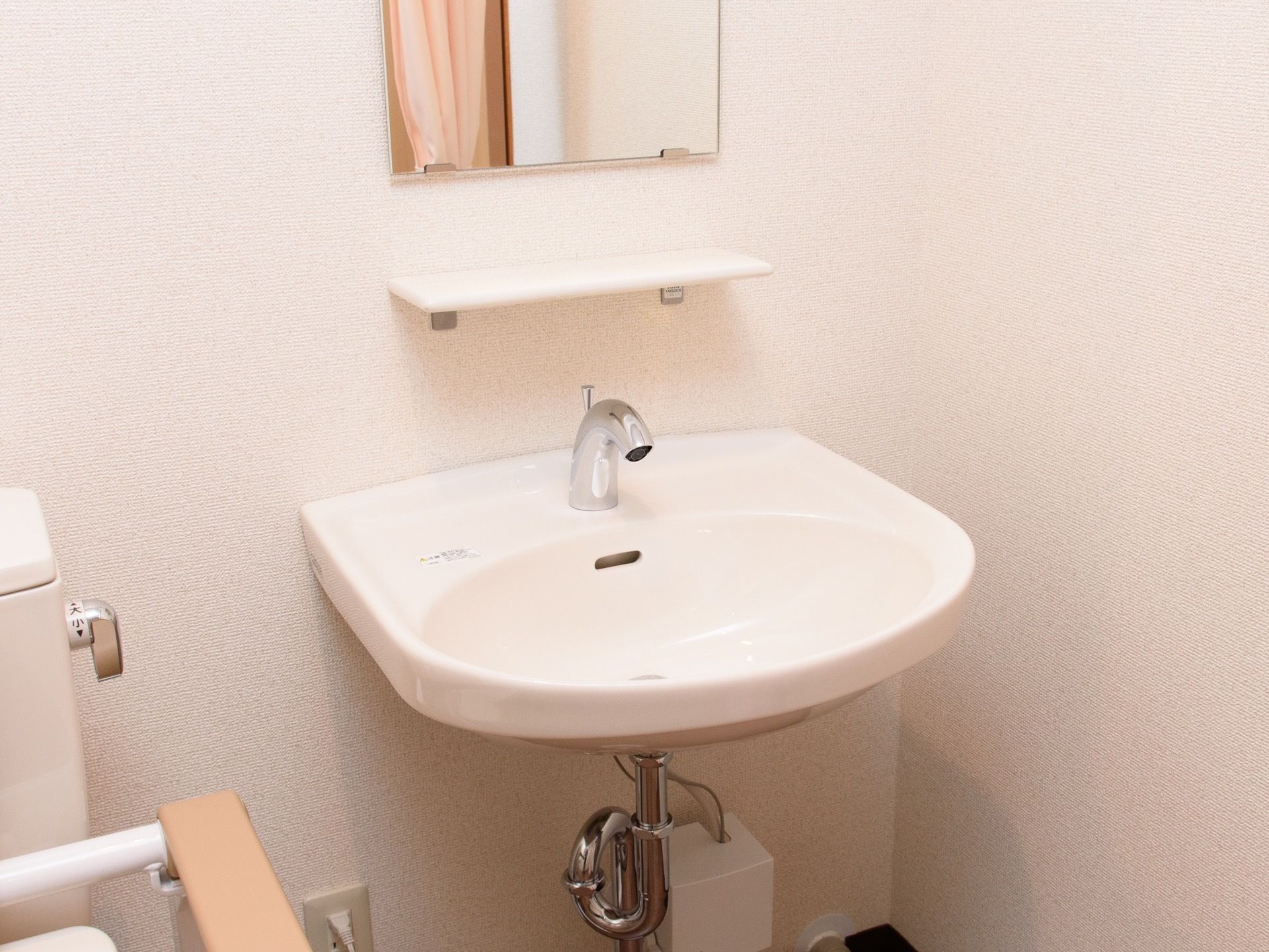 トイレの脇に自動水栓の洗面台が設置されている。足元にスペースがあり、車椅子をご利用の方も手を洗いやすくなっている。