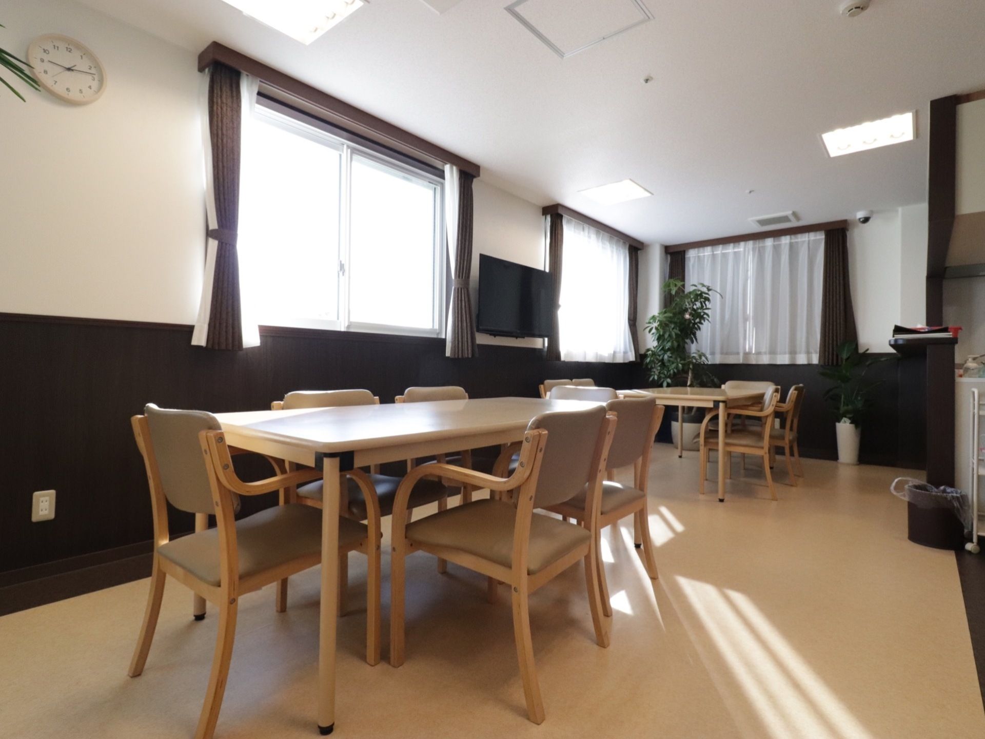テーブルが横に並べられ、それぞれに椅子が設置してある。窓が２つ並んでいる壁には、テレビが完備されている。