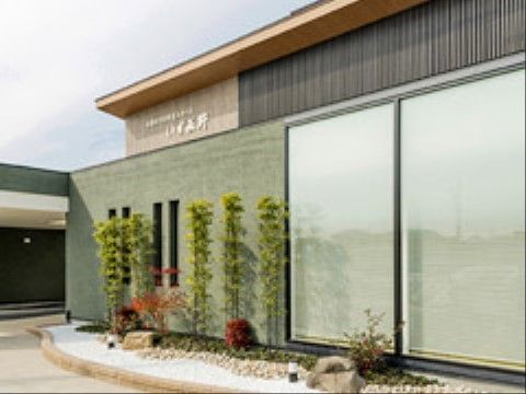 建物の前に、砂利が敷かれた小さな庭スペースのある施設の外観