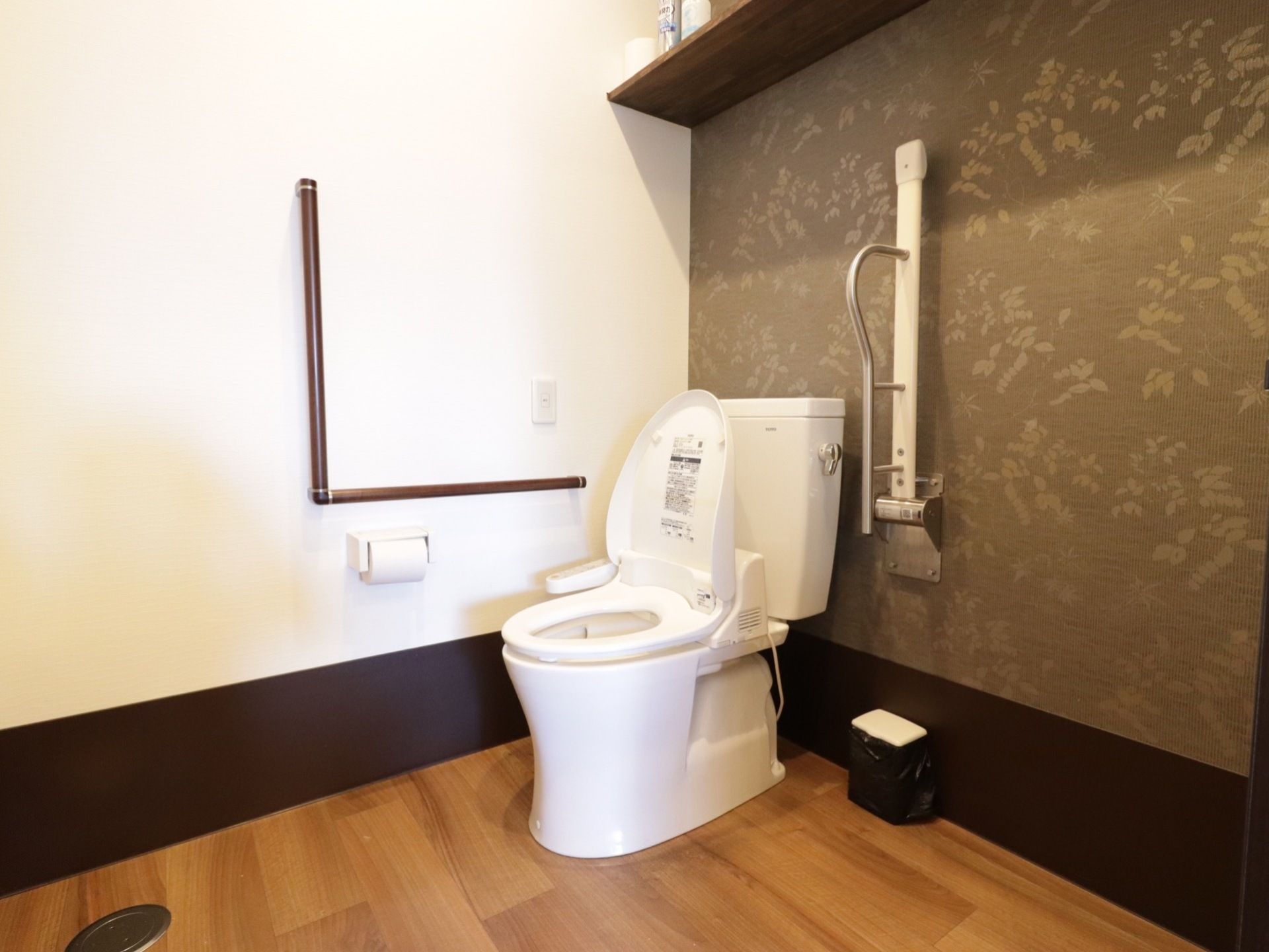 車椅子をご利用の方でも利用しやすい広いスペースのトイレには、壁と便器横に手すりが取り付けられている。ナースコールも付いている。